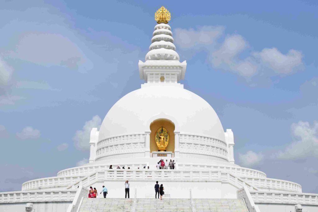 The majestic World Peace Pagoda (Shanti Stupa) in Lumbini, Nepal, featuring a brilliant white dome, golden spire, and a golden Buddha statue set within an alcove
